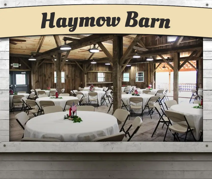 The rustic Haymow Barn set up for a catered event with white table cloths on round tables.